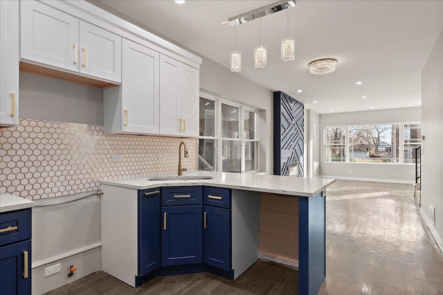 kitchen featuring sink, blue cabinetry, white cabinetry, tasteful backsplash, and decorative light fixtures