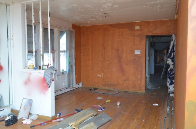 misc room with hardwood / wood-style floors, baseboard heating, and wood walls