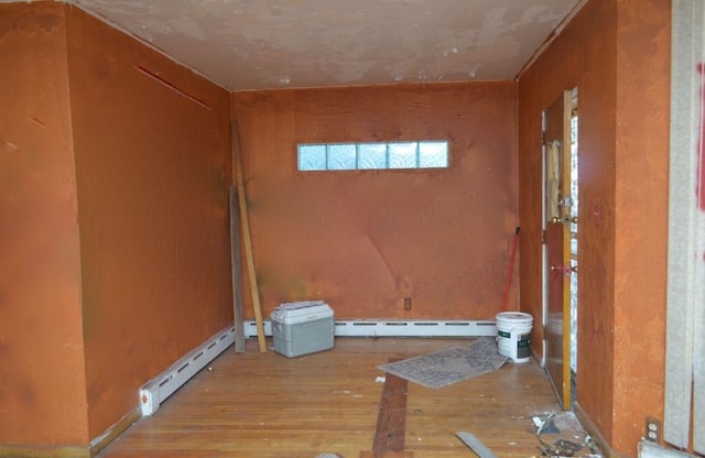 spare room featuring a baseboard heating unit and light hardwood / wood-style flooring