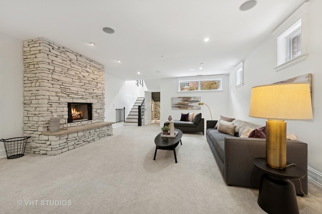 living room with a stone fireplace, stairway, light colored carpet, and recessed lighting