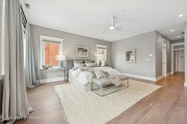 bedroom featuring a ceiling fan, wood finished floors, visible vents, and baseboards