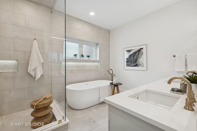 bathroom with tile patterned flooring, a sink, tile walls, a soaking tub, and double vanity