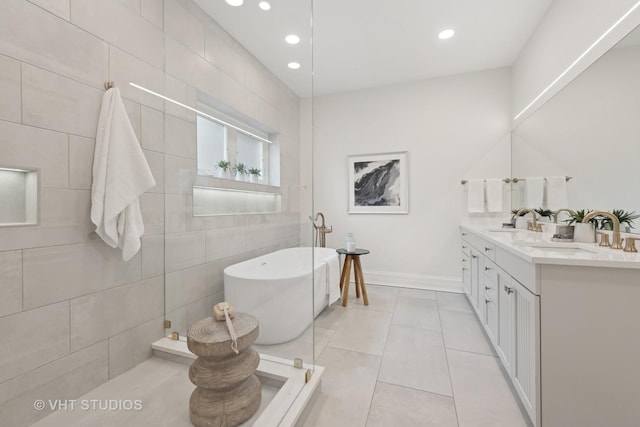 full bath with a freestanding tub, double vanity, a sink, and tile patterned floors