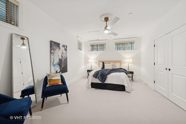 bedroom with a ceiling fan, a closet, light carpet, and baseboards