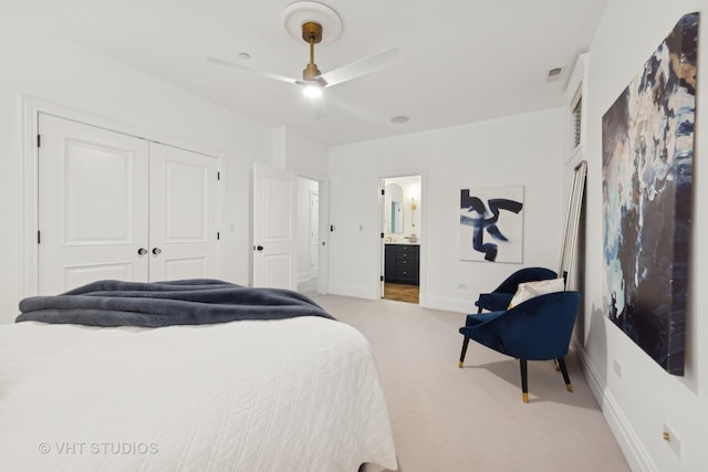 bedroom with a closet, light carpet, ceiling fan, ensuite bath, and baseboards