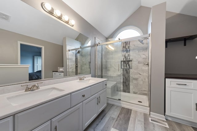 bathroom featuring an enclosed shower, vanity, vaulted ceiling, and wood-type flooring