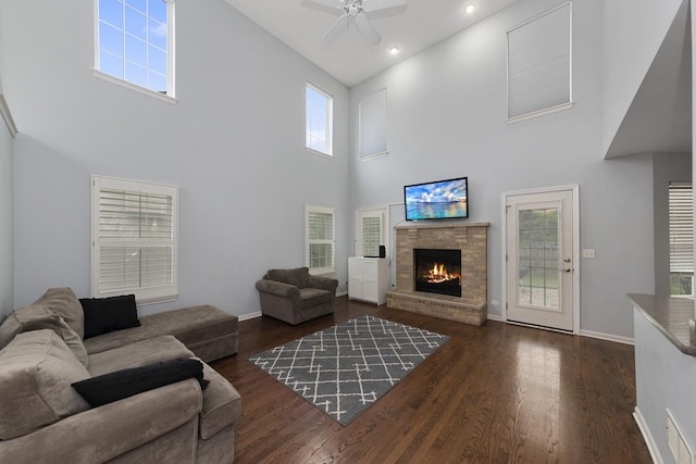 living room featuring a towering ceiling, a fireplace, dark wood-type flooring, and plenty of natural light