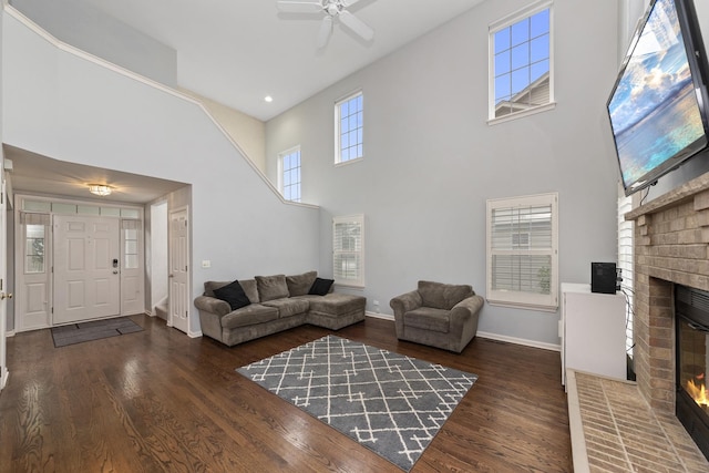 living room featuring a brick fireplace, dark wood-type flooring, and a high ceiling