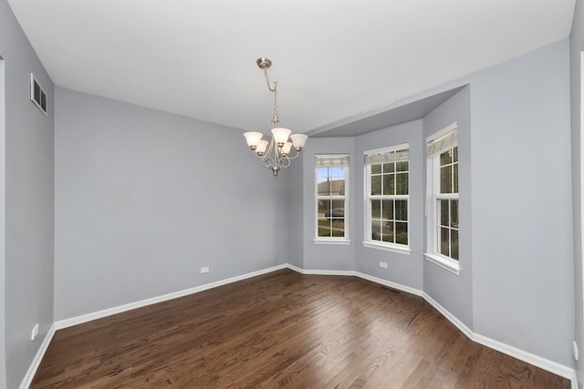 empty room with a notable chandelier and dark wood-type flooring