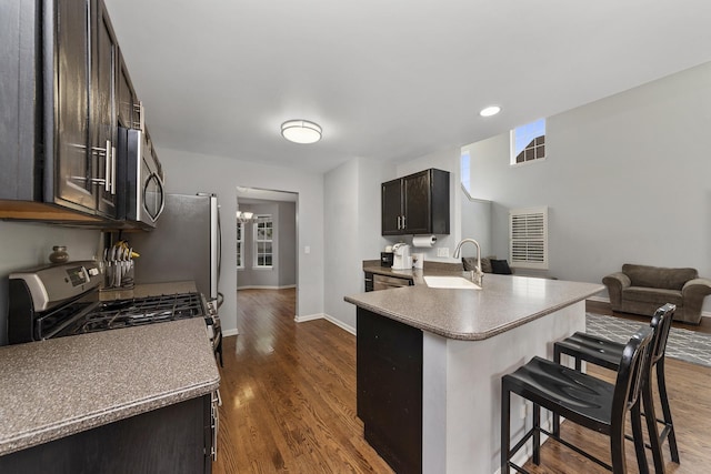 kitchen featuring sink, a breakfast bar area, kitchen peninsula, stainless steel appliances, and dark wood-type flooring