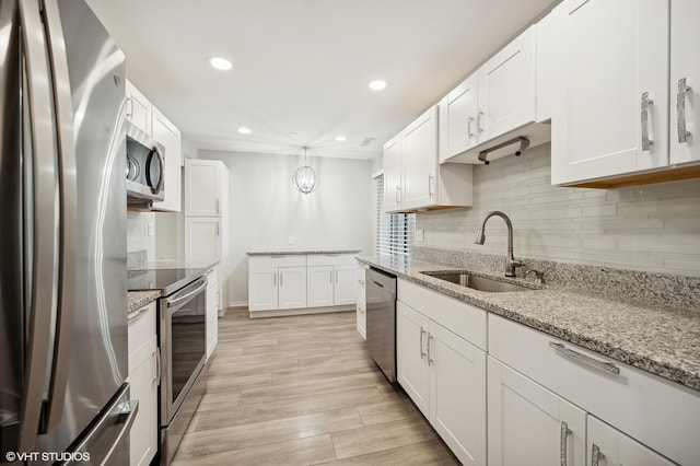 kitchen with sink, stainless steel appliances, white cabinets, and light stone countertops