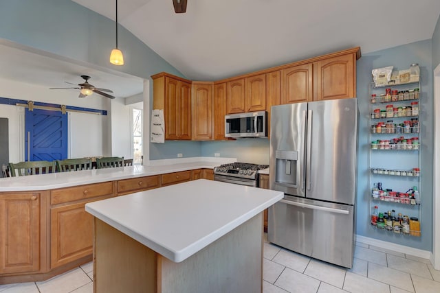 kitchen featuring decorative light fixtures, ceiling fan, kitchen peninsula, stainless steel appliances, and a barn door