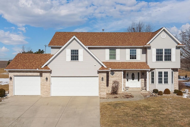 traditional-style house with a shingled roof, a front lawn, concrete driveway, and brick siding