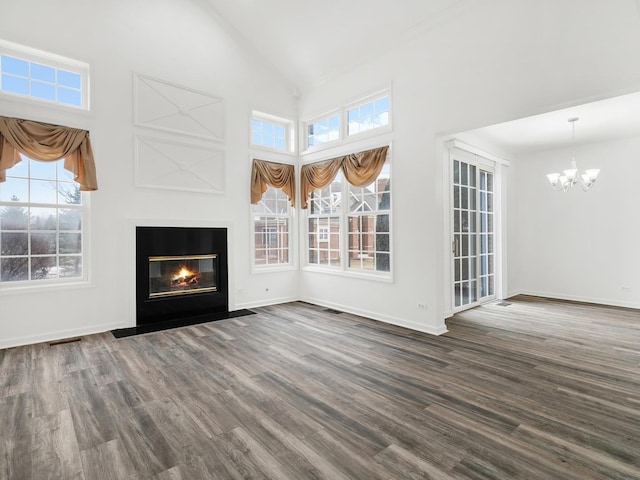 unfurnished living room featuring dark wood-type flooring, an inviting chandelier, and a towering ceiling