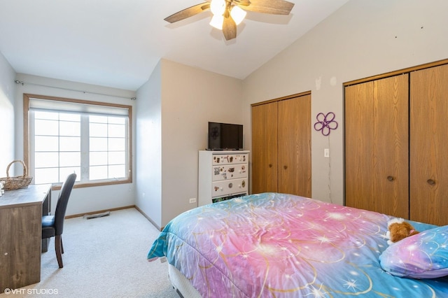 bedroom with multiple closets, lofted ceiling, light colored carpet, and ceiling fan