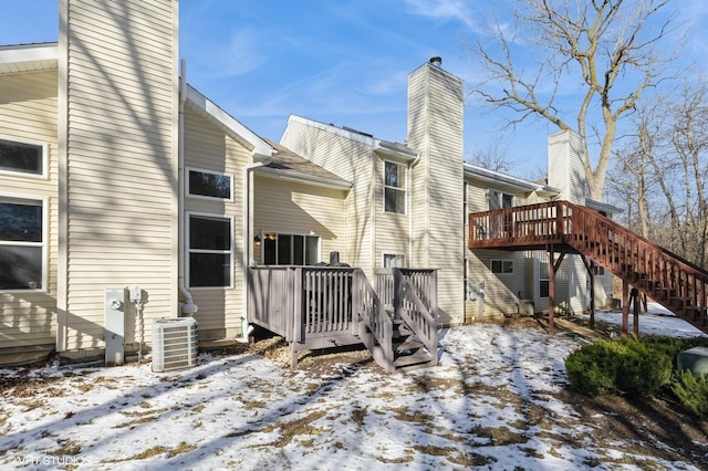 snow covered rear of property with a deck and central air condition unit