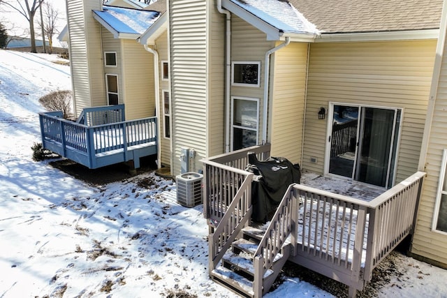 snow covered house with central air condition unit and a deck