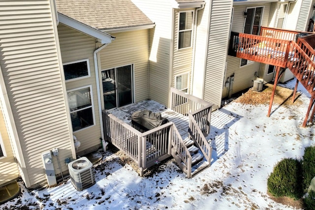 snow covered patio with a wooden deck and central AC unit