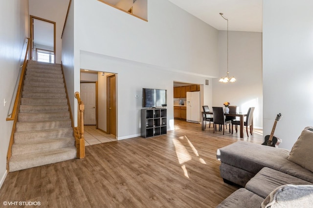 living room with a notable chandelier, light hardwood / wood-style floors, and a high ceiling