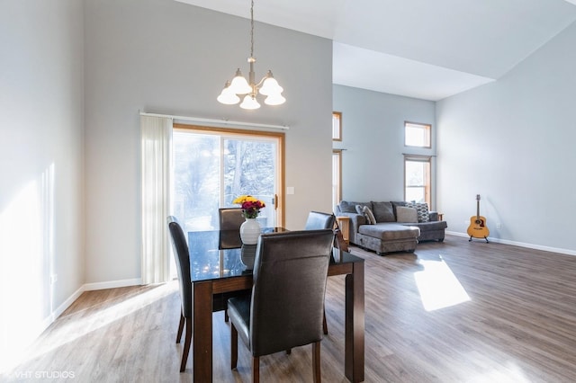 dining room with hardwood / wood-style flooring, plenty of natural light, a notable chandelier, and high vaulted ceiling