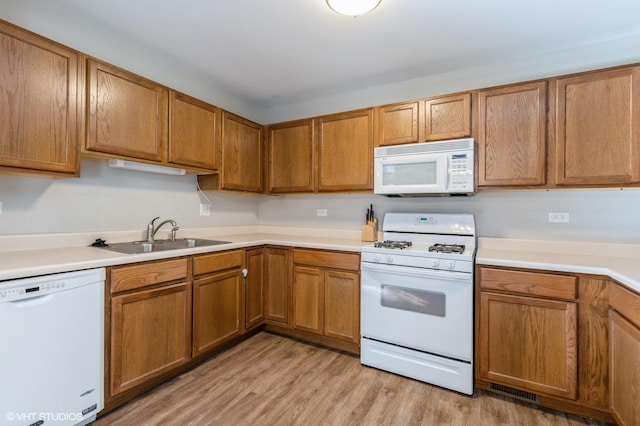 kitchen with sink, white appliances, and light wood-type flooring