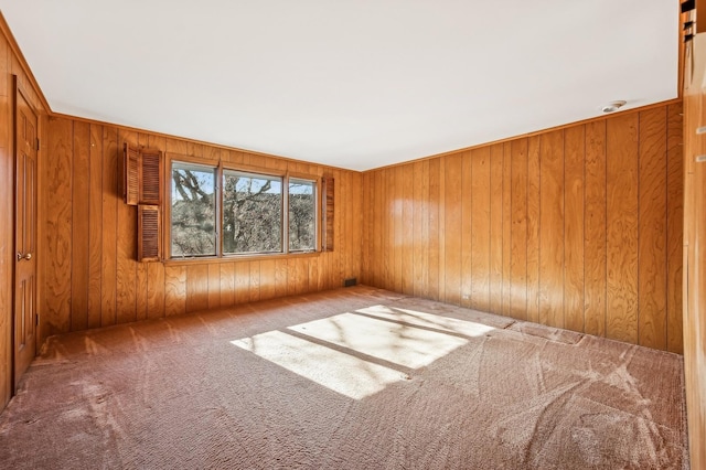 unfurnished room featuring light colored carpet and wooden walls