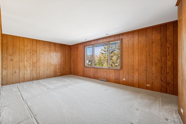 unfurnished room featuring light colored carpet and wooden walls