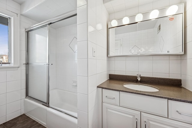 bathroom featuring tile walls, vanity, backsplash, and bath / shower combo with glass door