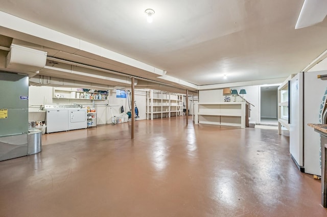 garage featuring white refrigerator, washing machine and dryer, and heating unit