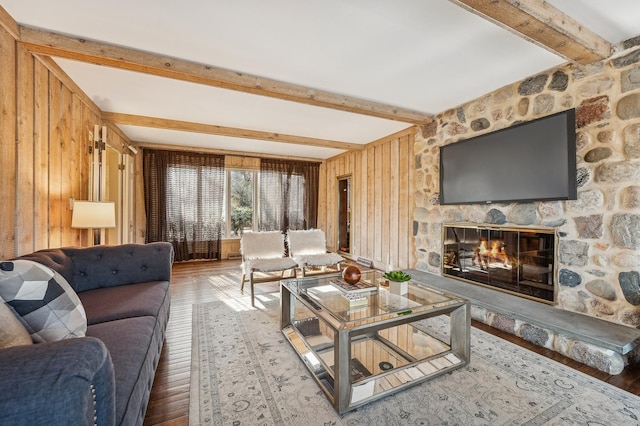 living room with hardwood / wood-style floors, beam ceiling, and a fireplace