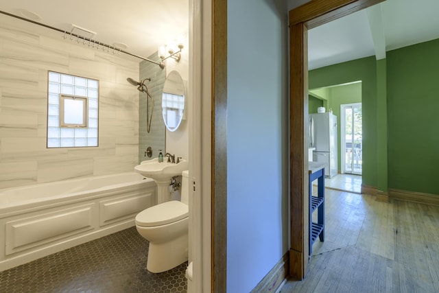 full bathroom featuring hardwood / wood-style flooring, toilet, tiled shower / bath combo, and sink