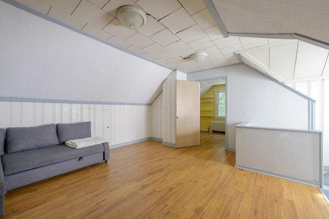 additional living space with lofted ceiling, radiator, and light hardwood / wood-style flooring