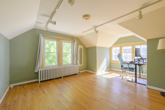 additional living space with lofted ceiling, radiator, a wealth of natural light, and light hardwood / wood-style flooring