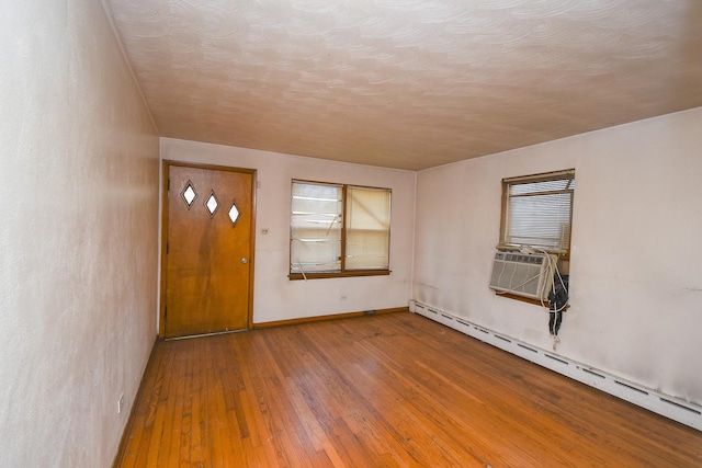 foyer entrance with hardwood / wood-style flooring, a baseboard heating unit, and cooling unit