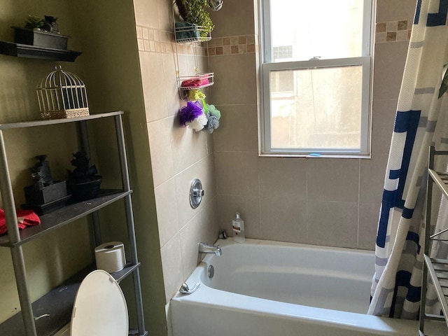 bathroom featuring shower / bathtub combination with curtain, toilet, and a healthy amount of sunlight