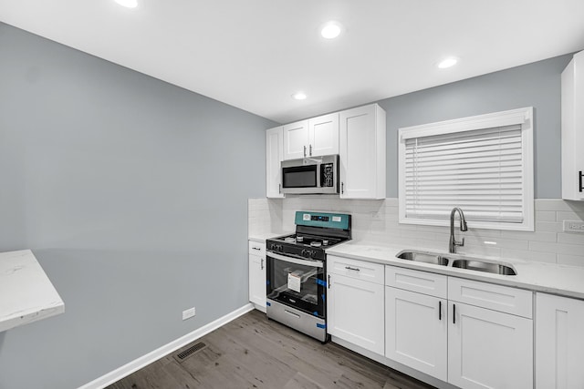 kitchen featuring stainless steel appliances, sink, white cabinets, and decorative backsplash