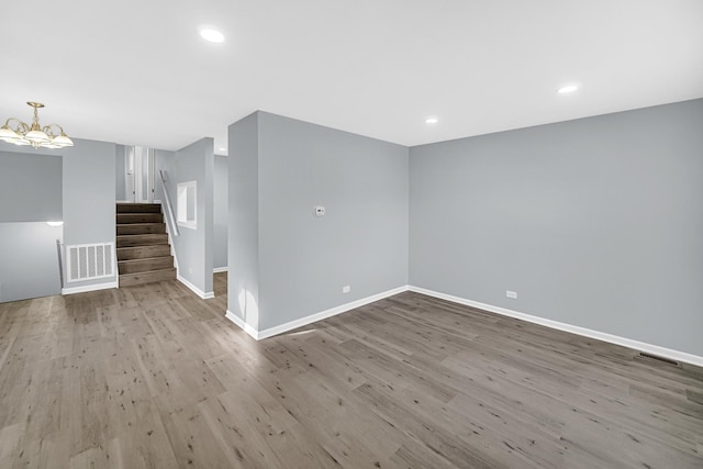 empty room with an inviting chandelier and light hardwood / wood-style flooring