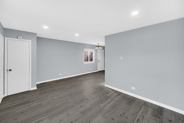 empty room with dark wood-type flooring and a notable chandelier