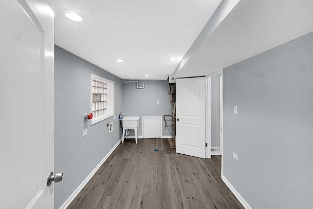 clothes washing area featuring wood-type flooring and sink