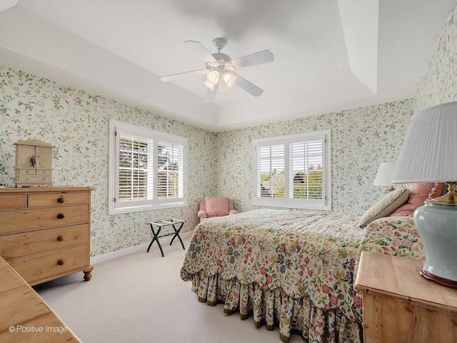 bedroom featuring light carpet, ceiling fan, and a tray ceiling