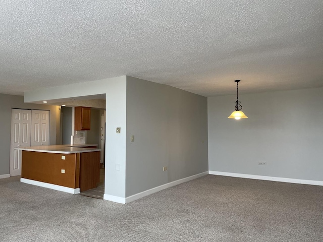 unfurnished living room with baseboards, light colored carpet, and a textured ceiling