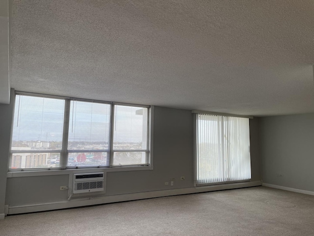 empty room with a wealth of natural light, baseboards, carpet floors, and a textured ceiling