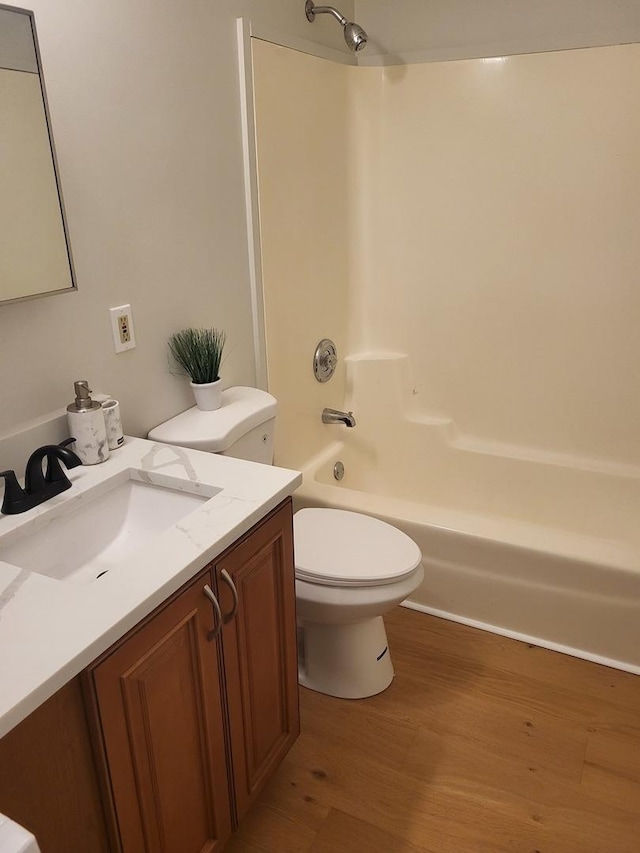 full bathroom with hardwood / wood-style flooring, shower / bathtub combination, vanity, and toilet