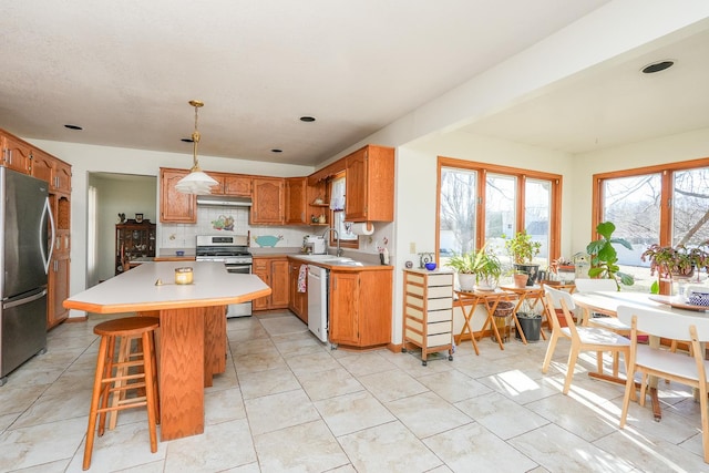 kitchen featuring sink, a breakfast bar area, hanging light fixtures, appliances with stainless steel finishes, and a kitchen island