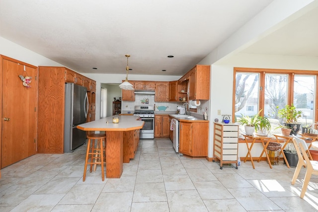 kitchen featuring a breakfast bar, sink, decorative light fixtures, a kitchen island, and stainless steel appliances