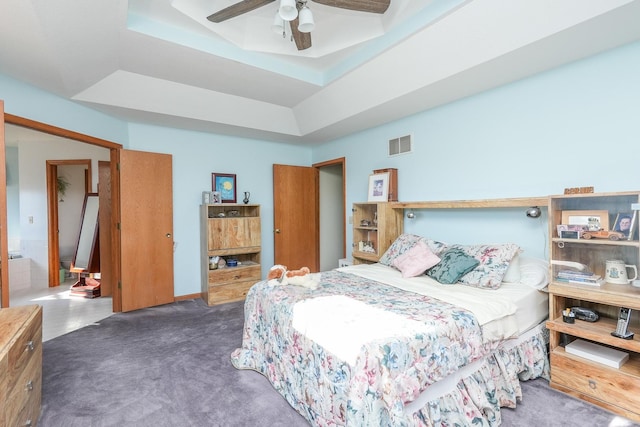 bedroom with dark carpet, a tray ceiling, and ceiling fan