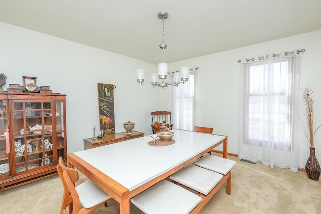 carpeted dining area with a chandelier