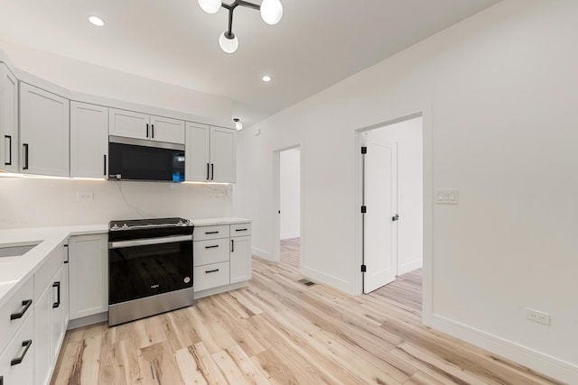 kitchen with stainless steel stove, tasteful backsplash, white cabinetry, sink, and light hardwood / wood-style floors