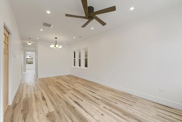 unfurnished room featuring ceiling fan with notable chandelier and light hardwood / wood-style floors