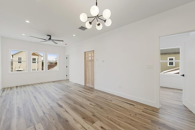 unfurnished living room with ceiling fan with notable chandelier and light hardwood / wood-style flooring